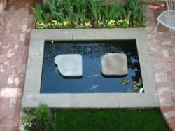 Koi pond incorporated into pathway between two patios.