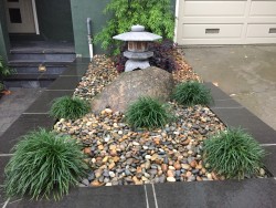 Close up of Asian accent, stone lantern and green accents in a bed of river pebbles