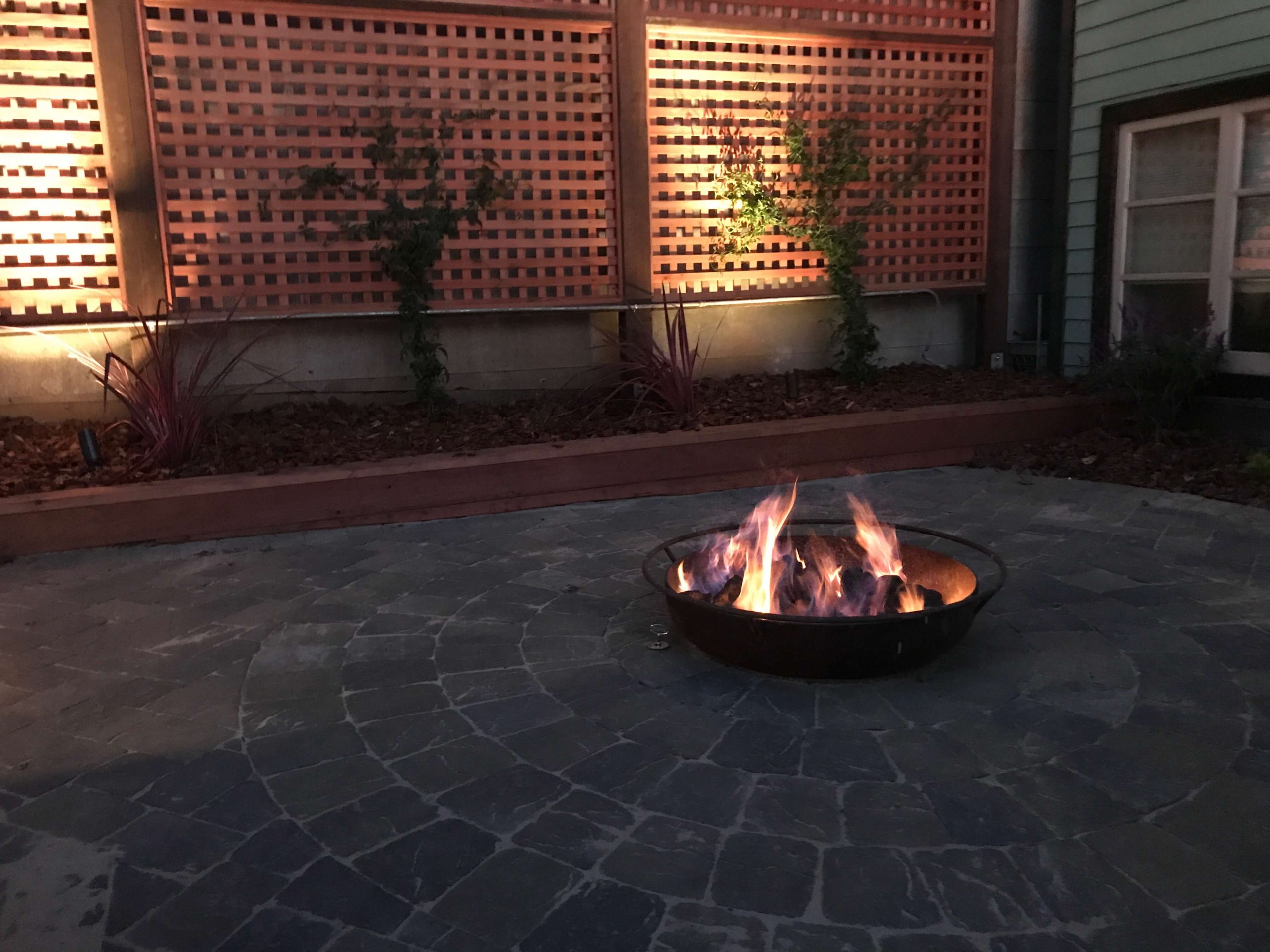 Backyard Landscape Project: Lower patio, made with interlocking pavers, holds a fire pit made from an Iron dish, customized to accept a natural gas fire ring
