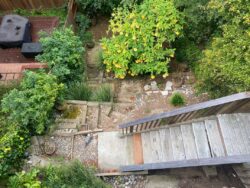 Ashbury Heights project backyard before demo. Steep hillside with crumbling retaining walls and stairs.