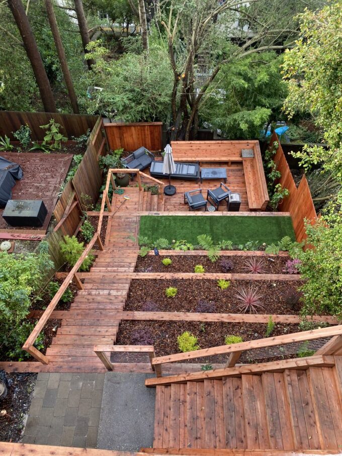 Ashbury Heights project with five retaining walls, two decks, stairs, bench area, and stainless steel cable system. Artificial turf on bottom level of retaining wall and plants on other levels.