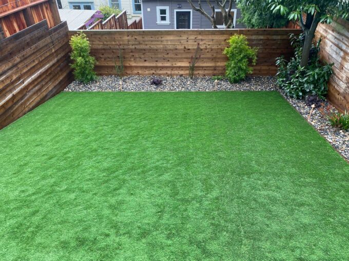 Completed artificial turf installation in Sunnyside neighborhood of San Francisco. Turf surrounded by border plants on right and back side.