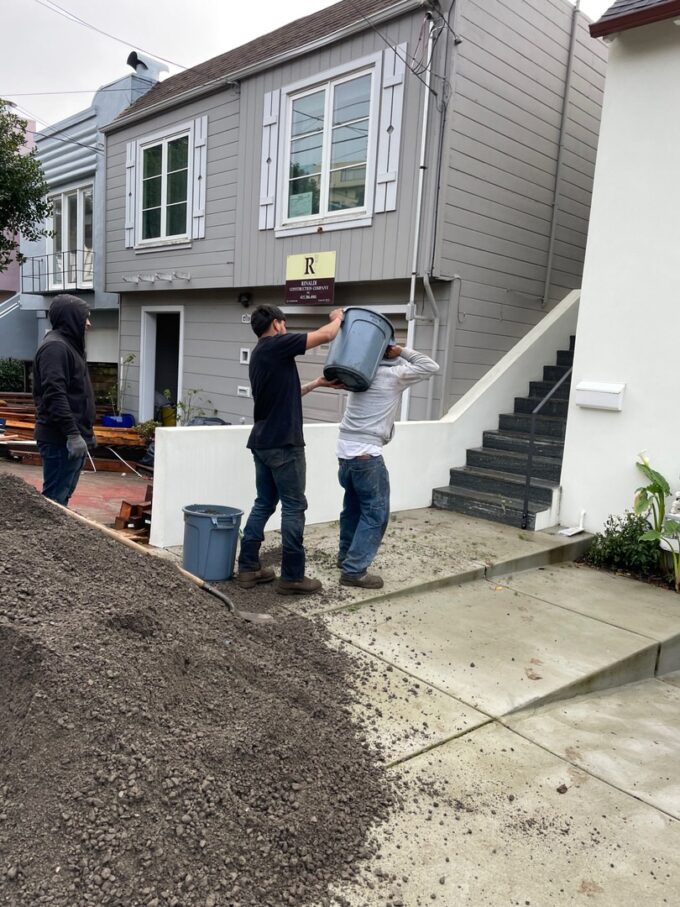 Carrying 80 pounds of base rock in blue 10 gallon bucket on the back of worker up through he house to the backyard of our Sunnyside, San Francisco project.