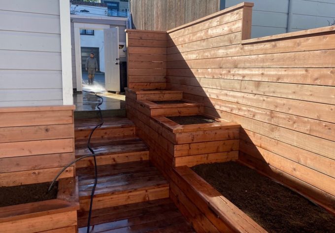 Three steps completed from back entrance of property. On right of steps are four levels of raised planters.