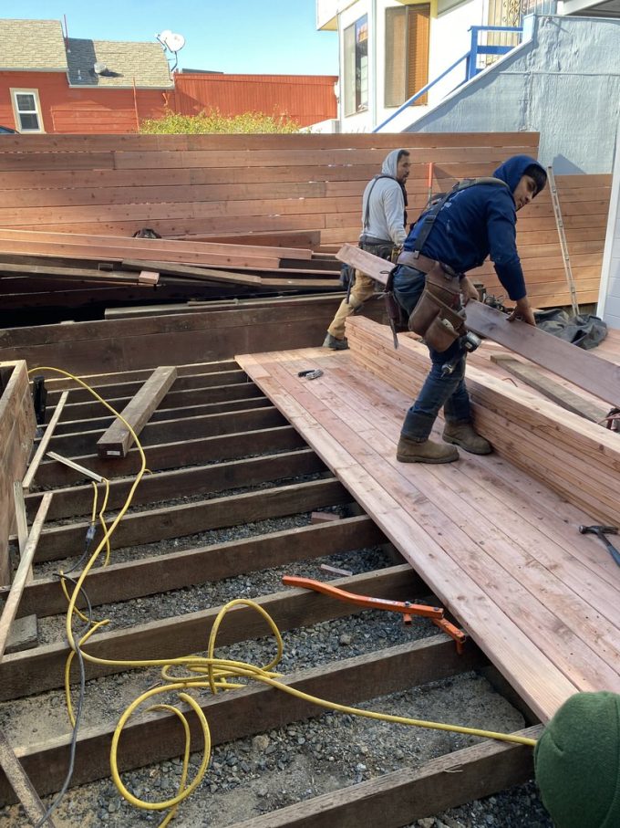 Deck installation in progress with new redwood fence in background.