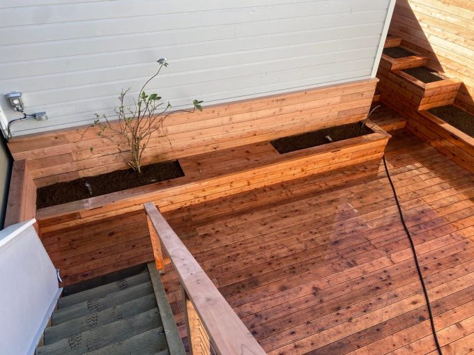 Looking down from stairs at completed raised planters at back of wall and on right side of deck.
