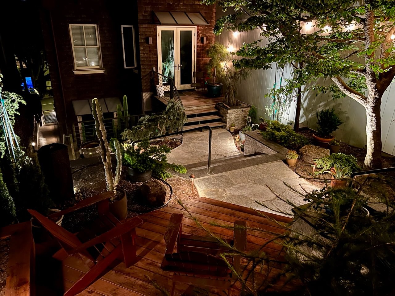 Completed redwood deck in foreground and quartzite flagstone walkway at night.