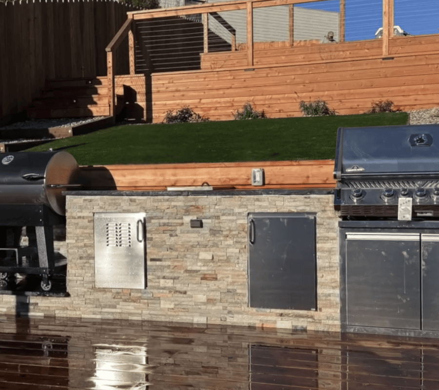 Tamate Landscaping employee works on a project in Inner Sunset with retaining walls, an outdoor kitchen, stone patio, and wood deck